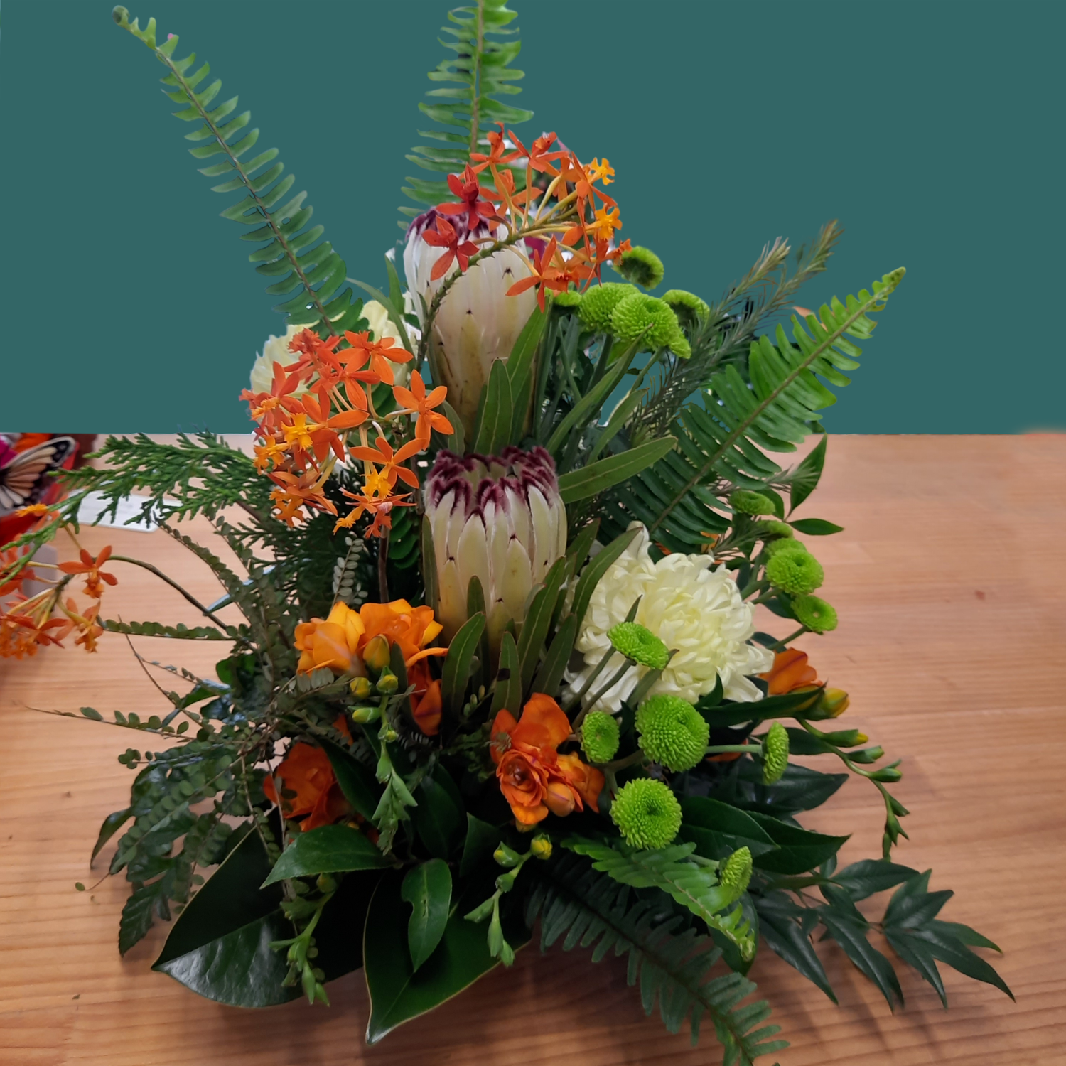 Floral arrangement with orange, white, and green flowers on a wooden surface