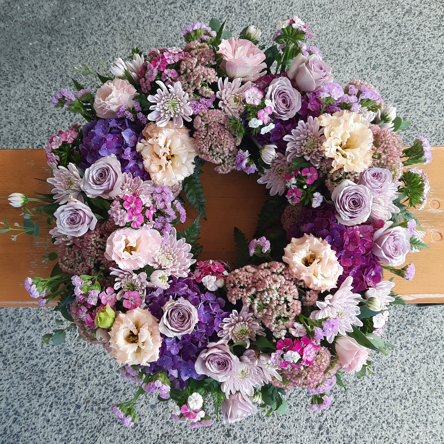 Floral wreath with a variety of flowers on a wooden surface.